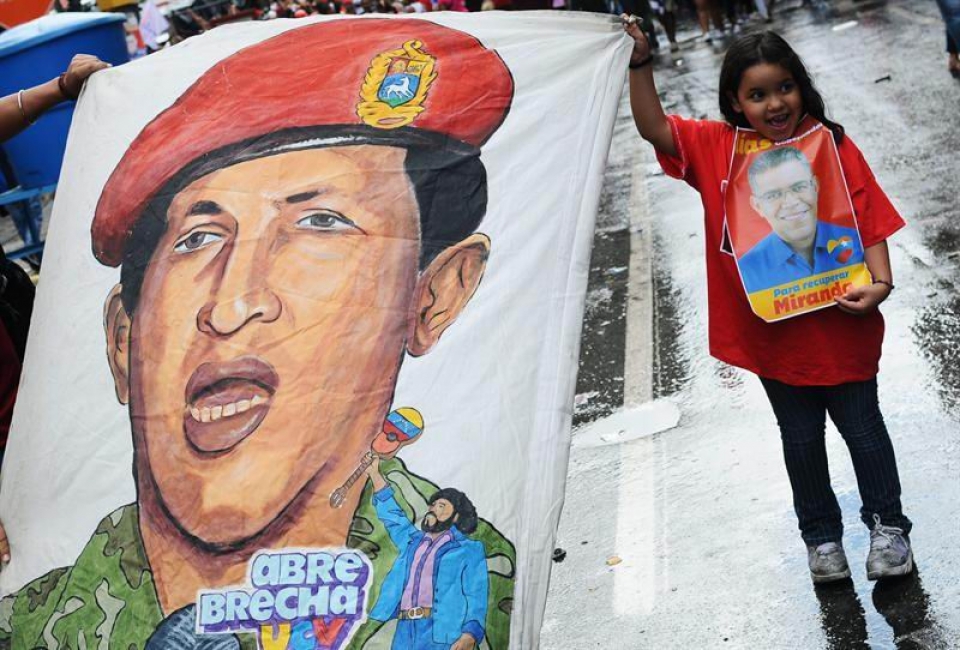 Una niña con una cartel electoral de Hugo Chávez. Foto: EFE