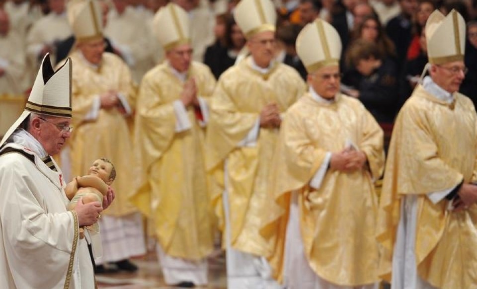 El papa Francisco sostiene una estatua del niño Jesús. 