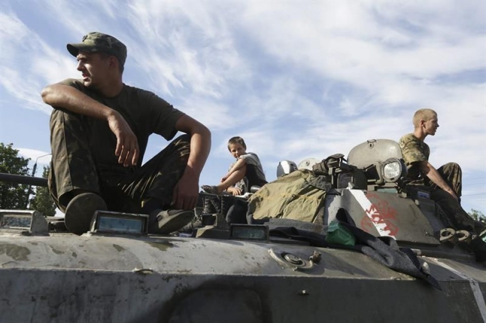 Varios soldados ucranianos y un niño descansan sobre un tanque en Donetsk. Foto: EFE