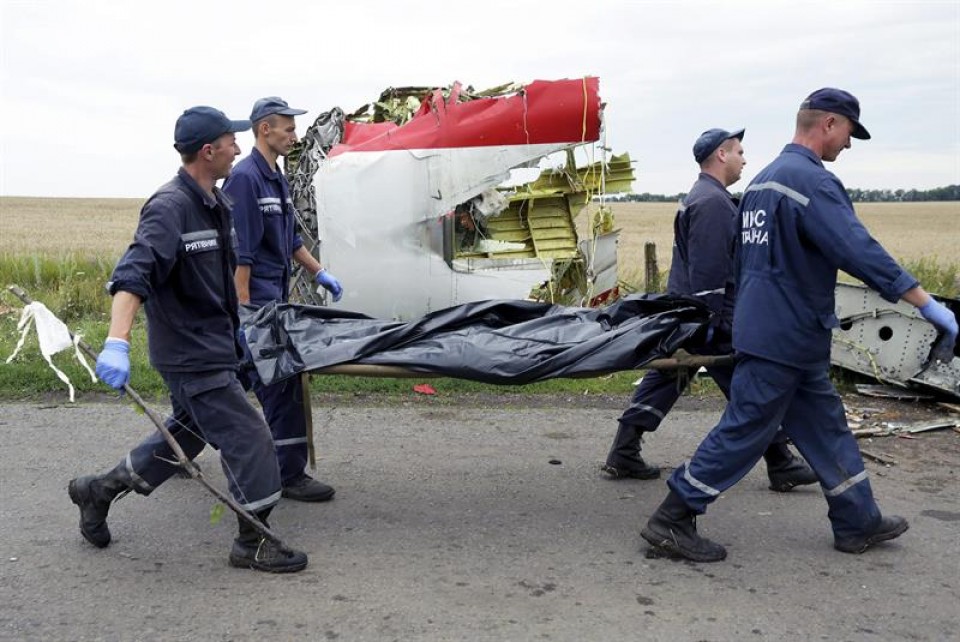Miembros de los grupos de rescate trasladan a una víctima, frente a los restos del avión. Foto: EFE