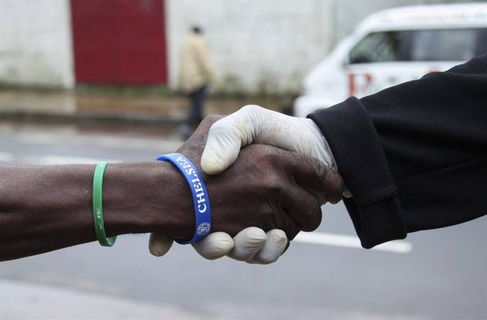 Un hombre usa guantes de plástico al saludar para prevenir el virus del ébola. EFE