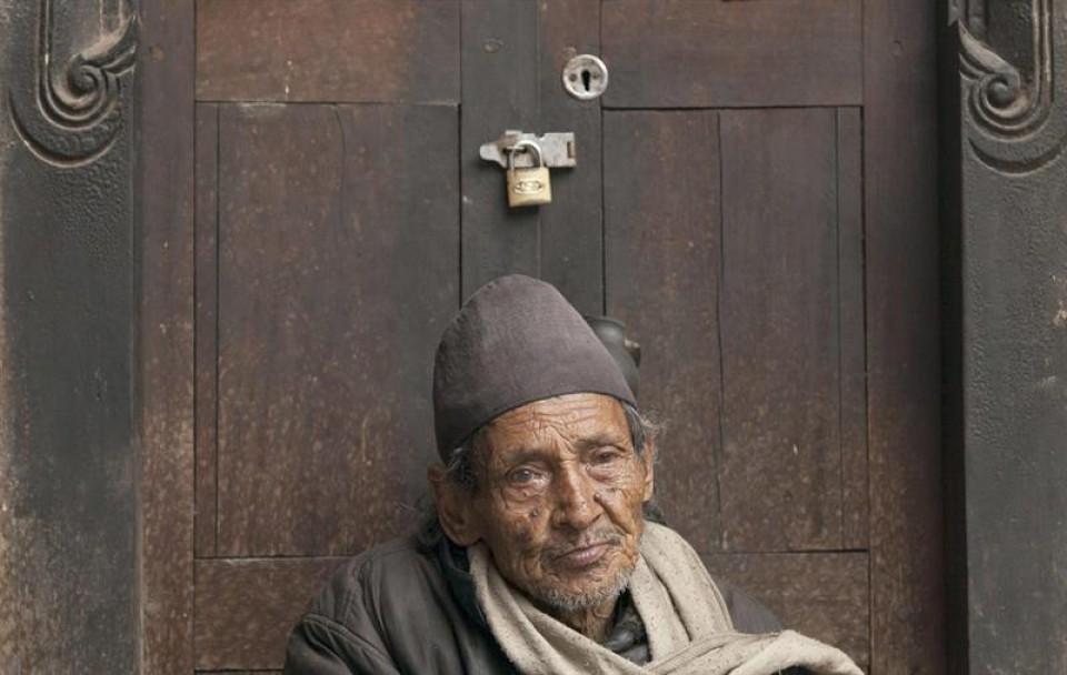 Un hombre descansa en la puerta de una casa cerrada, en Katmandú. Foto: EFE