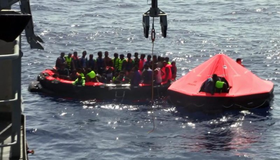 Inmigrantes sentados en barcos inflables durante el rescate frente a las costas de Libia. Foto. EFE