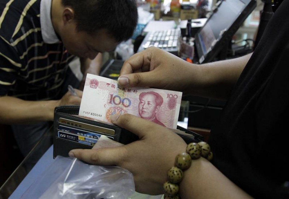 Un cliente saca un billete de 100 yuanes en una tienda de Pekín. Imagen de archivo: EFE