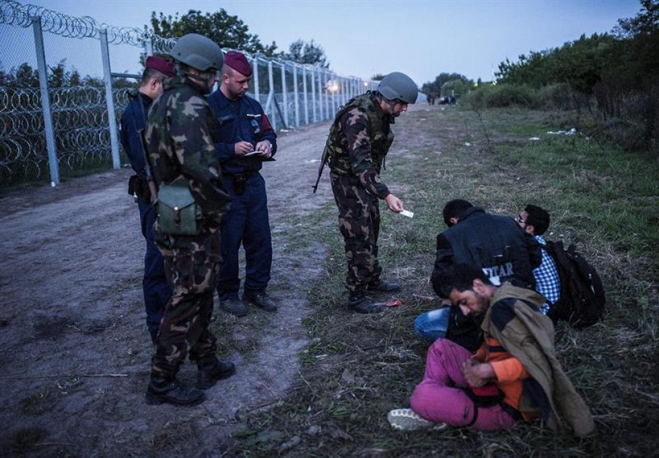 Policías y soldados comprueban la documentación de varios refugiados cerca de Roszke. Foto: EFE