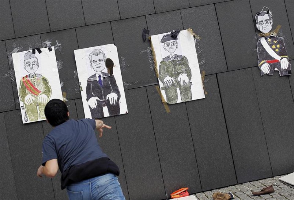 Un participante lanza su zapato a carteles con dibujos de altos cargos nacionales y mundiales. EFE