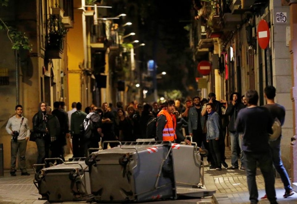 Los cuerpos antidisturbios ante varios manifestantes, a la entrada del "banco expropiado". EFE.