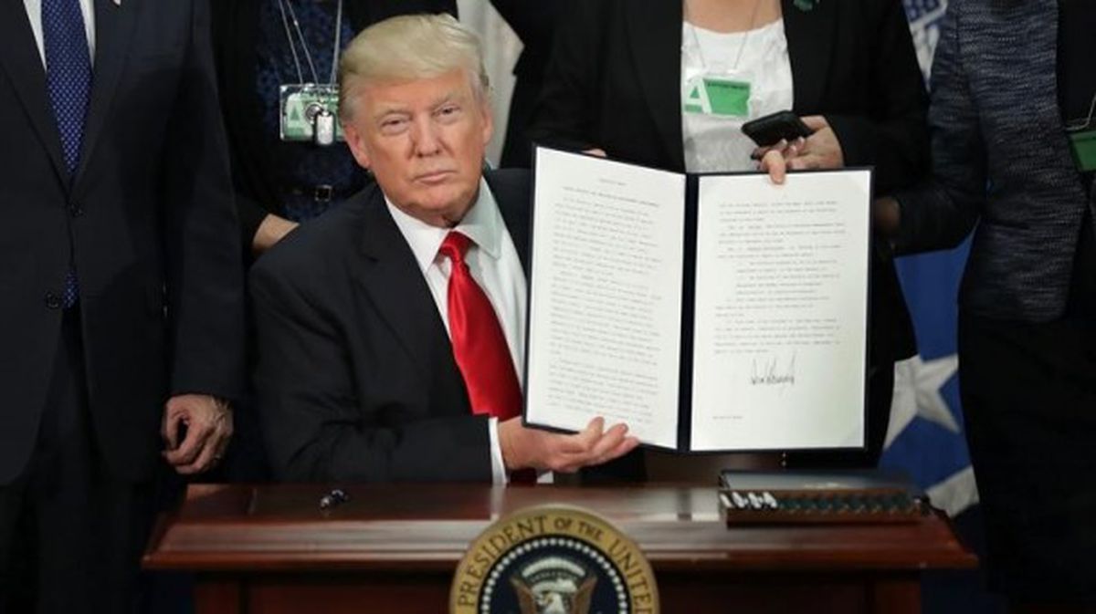 Donald Trump muestra la firma que autoriza la construcción del muro. Foto: EFE