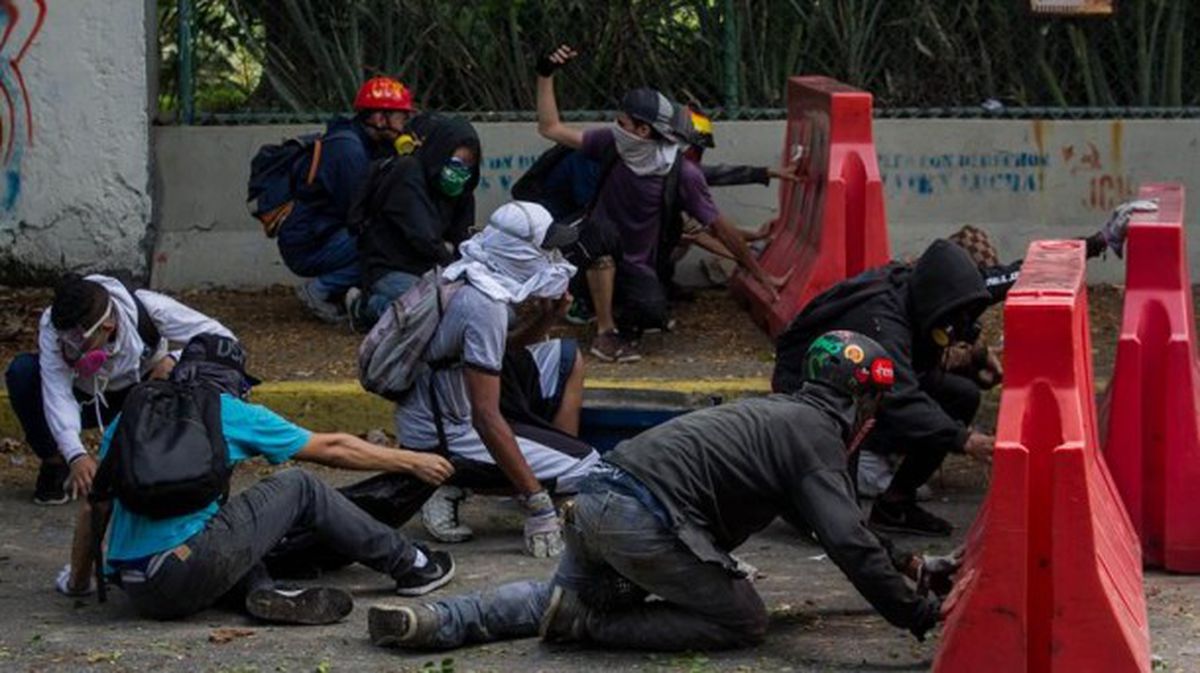 Manifestantes se protegen en una protesta en Venezuela. Foto: Efe