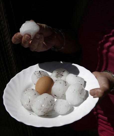 Una mujer muestra las bolas de granizo del tamaño de un huevo. Foto: EFE