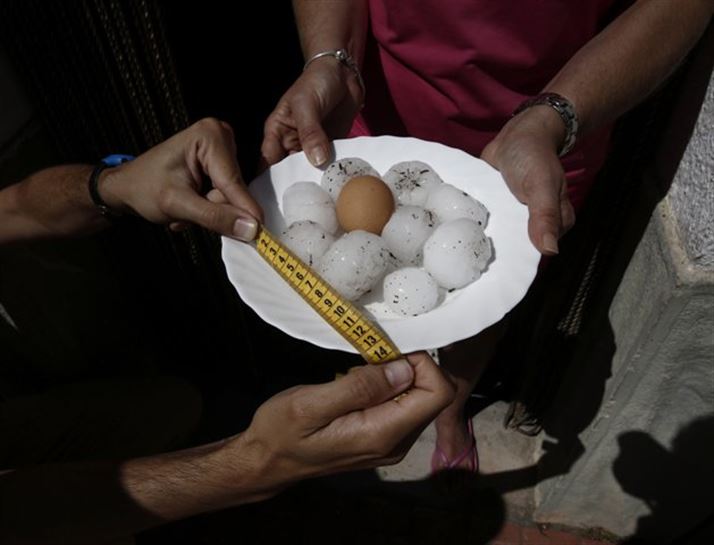 Una mujer muestra las bolas de granizo del tamaño de un huevo. Foto: EFE