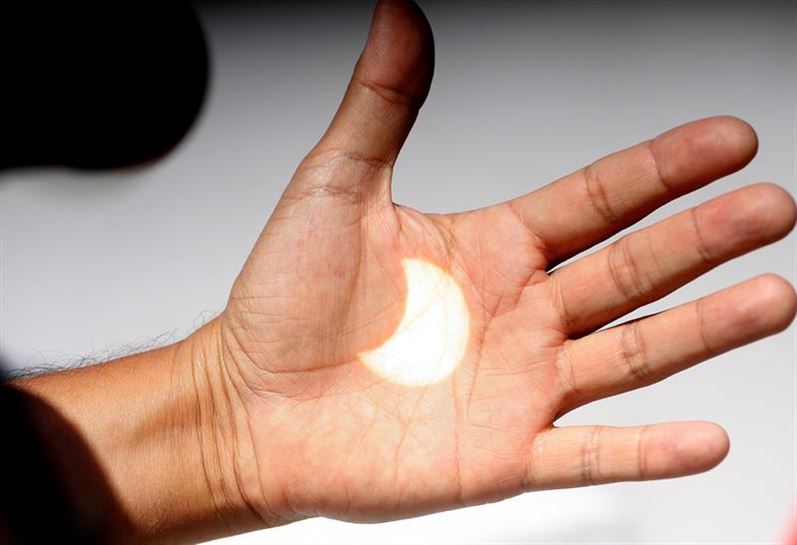 Un hombre muestra la imagen de un eclipse proyetada en su mano