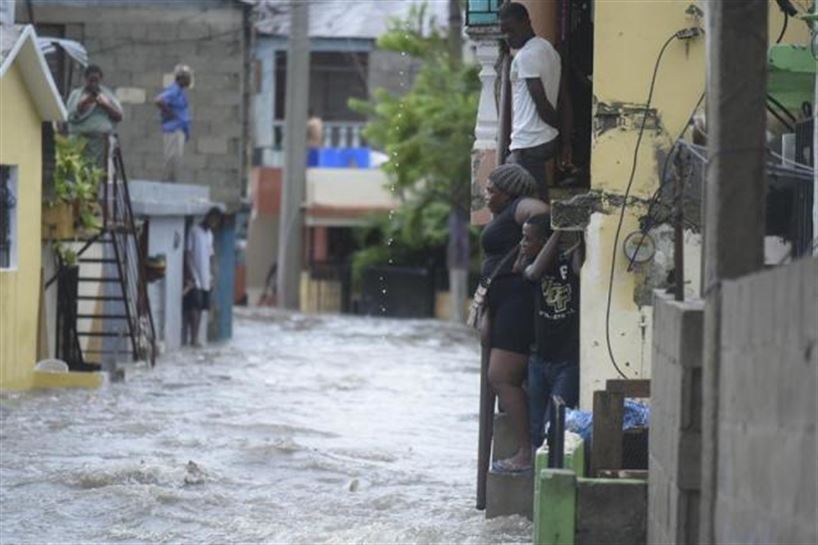 Personas observan una calle inundada en Santiago de los Caballeros (República Dominicana). Foto: EFE