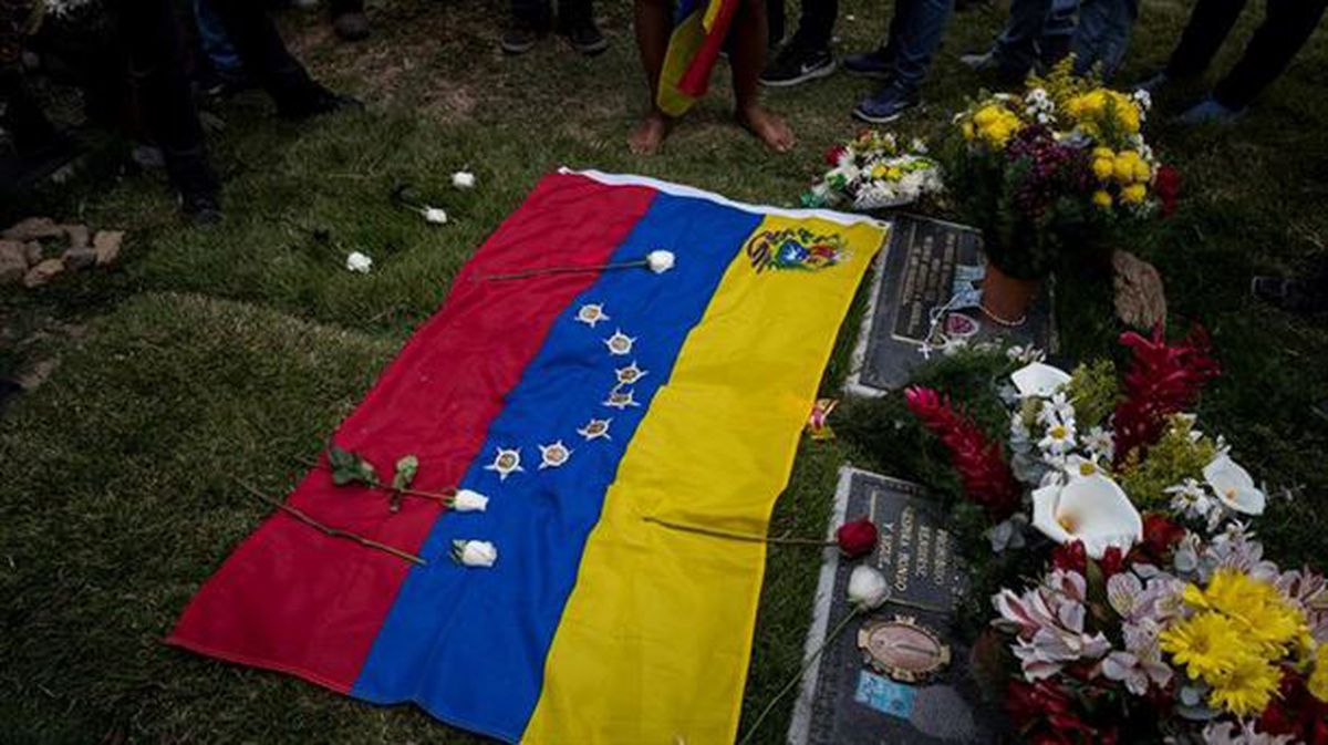Una bandera de Venezuela sobre el suelo adornada con flores en una calle de Caracas.