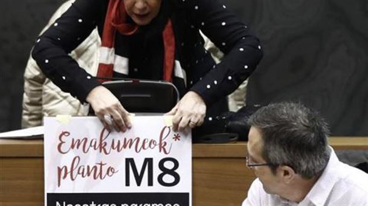La parlamentara de EH Bilbu, Miren Aranoa, coloca en su escaño un cartel en la Cámara navarra. Foto: EFE