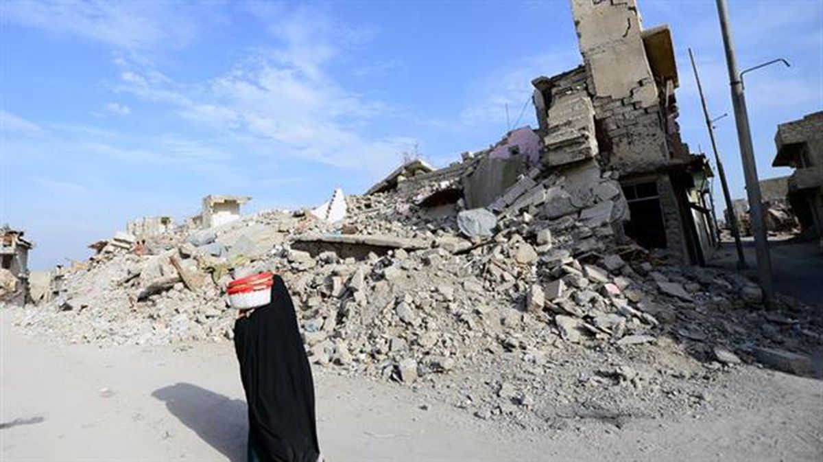 Emakume bat hondatuta dagoen eraikin baten albotik ibiltzen Mosulen (Irak). Argazkia: EFE