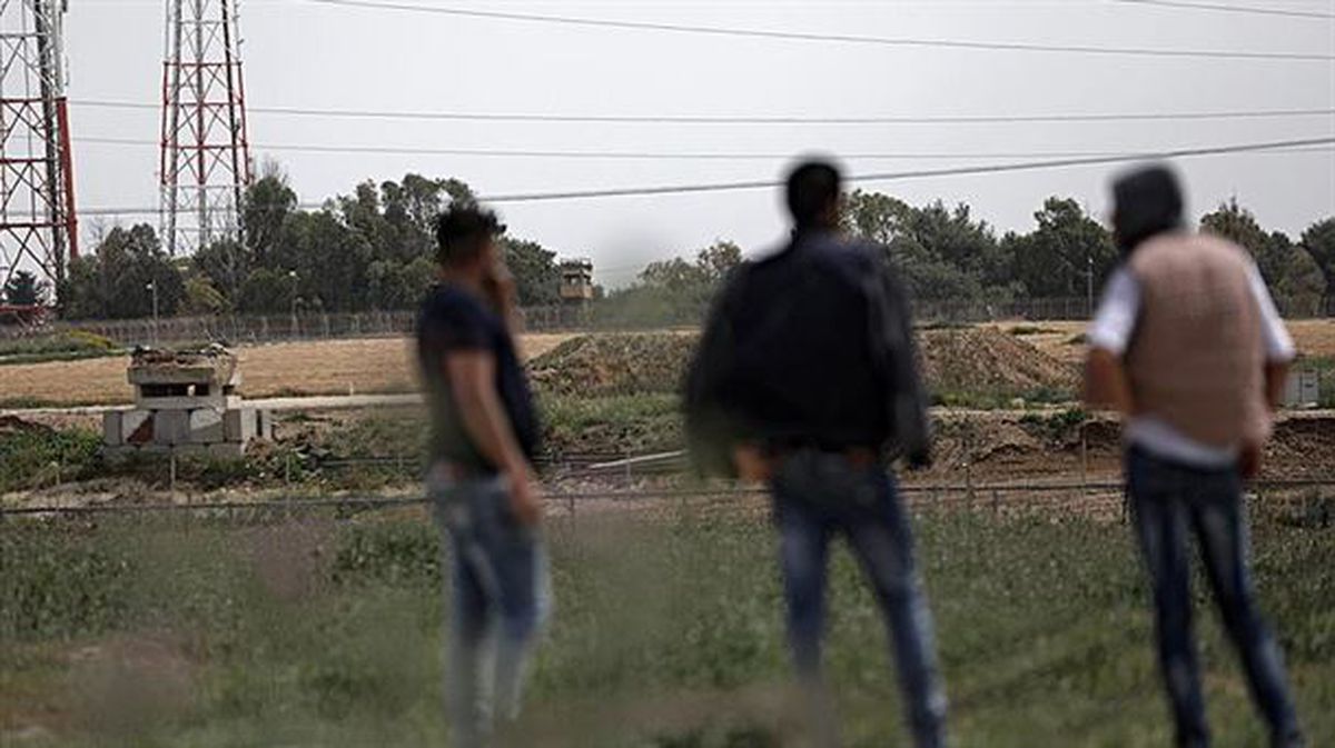 Varios palestinos observan torres militares israelíes en la Franja de Gaza. Foto: EFE