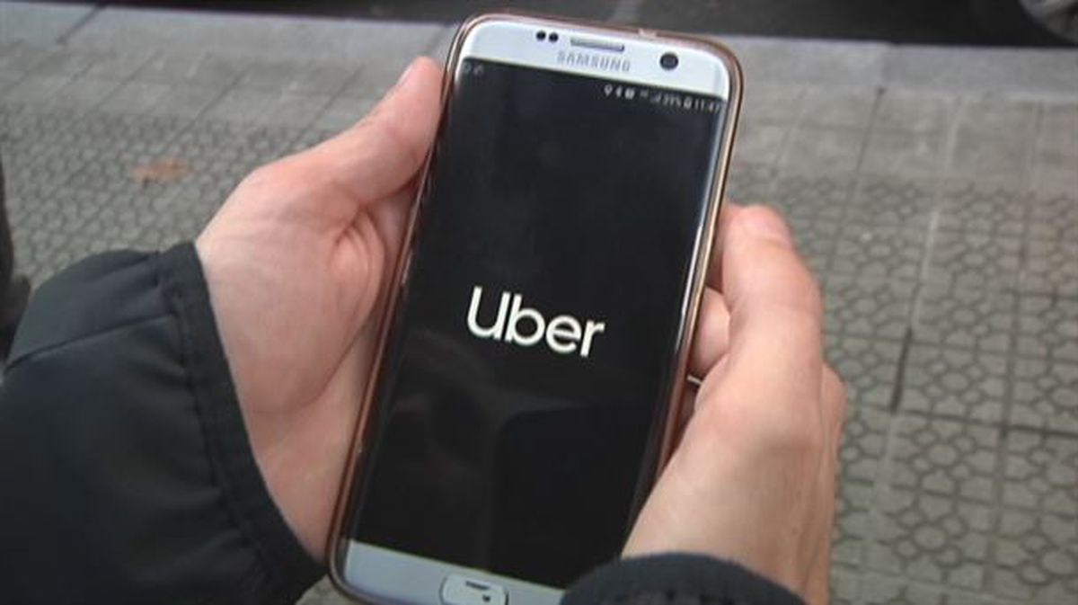 Uber zerbitzuaren erabiltzaile bat, mugikorra eskuan duela. 
