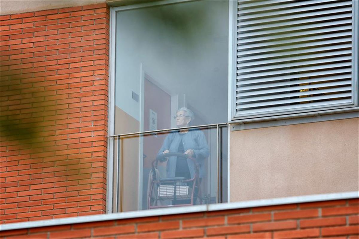Una persona mayor mira por la ventana de una residencia durante el confinamiento. 