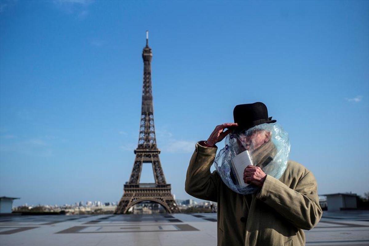 Un hombre cubierto con un plástico frente a la Torre Eiffel.