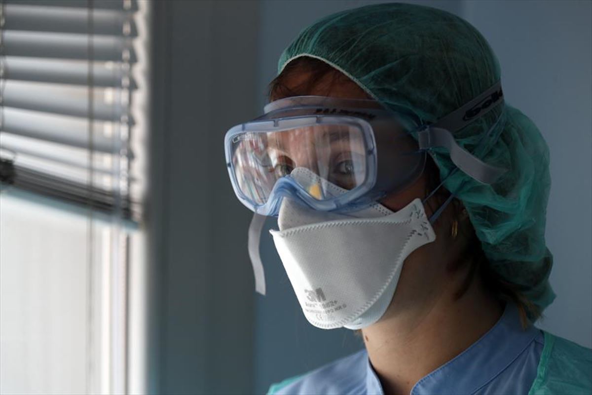 Imagen de una enfermera protegida con mascarilla, gafas y gorro.