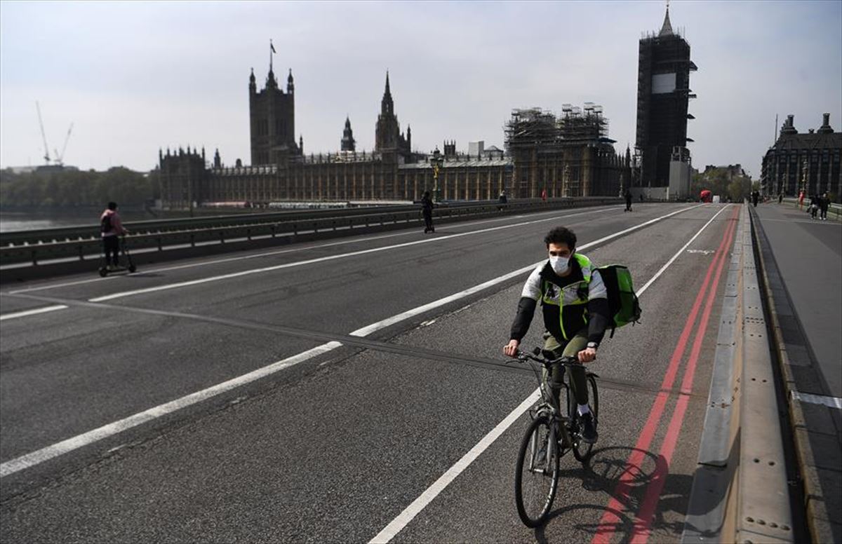 Una persona con mascarilla recorre Londres en bicicleta.