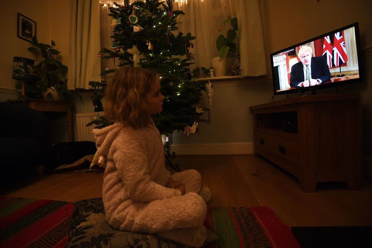 Una menor mira la televisión que ofrece el discurso de Boris Johnson.