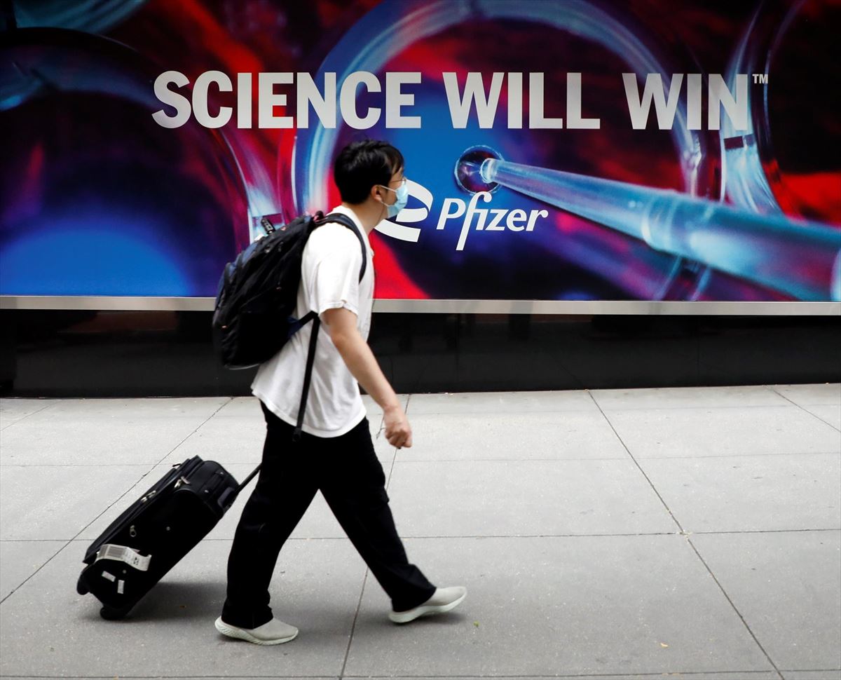Un hombre pasa por delante de un anuncio de Pfizer. 