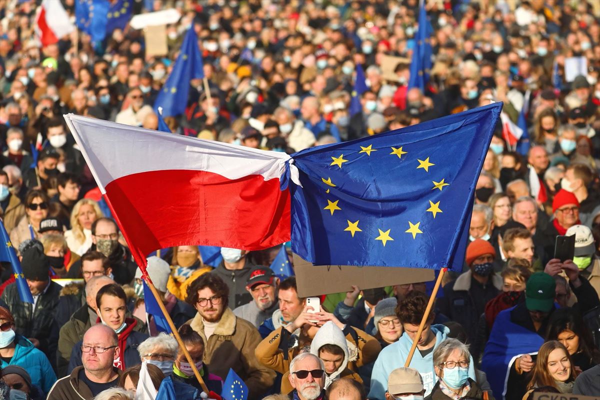 Las personas portan banderas polacas y de la UE durante una protesta en Cracovia, Polonia