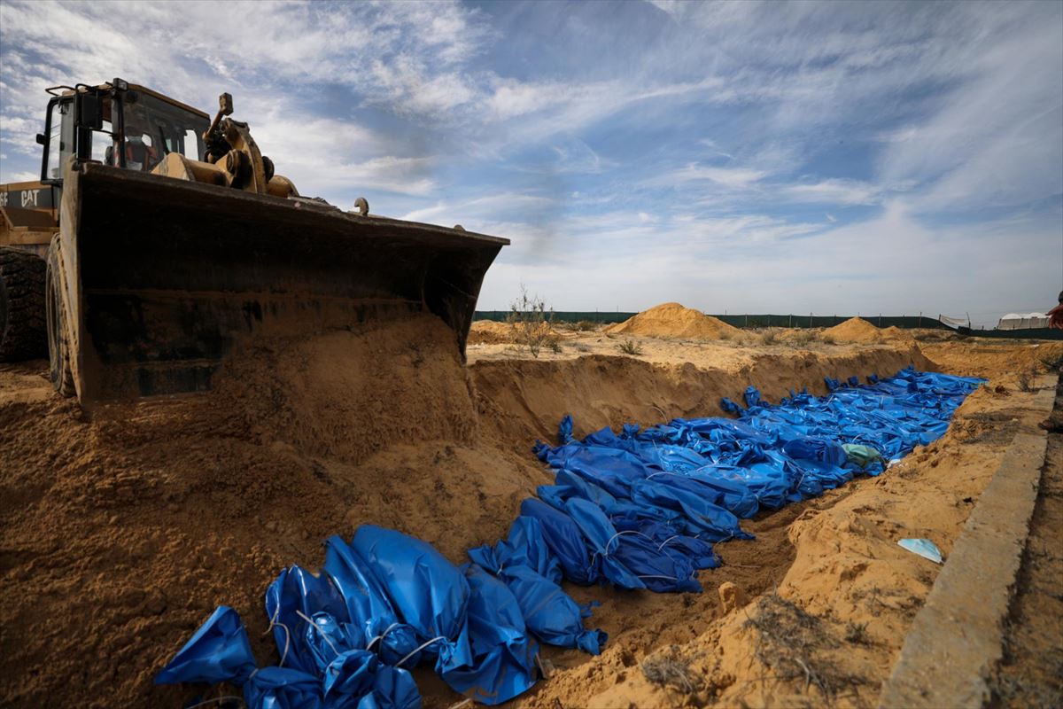 Una excavadora entierra los cuerpos de 111 palestinos muertos en ataques israelíes contra Gaza, en una fosa común en el cementerio de Khan Younis, en el sur de la Franja de Gaza