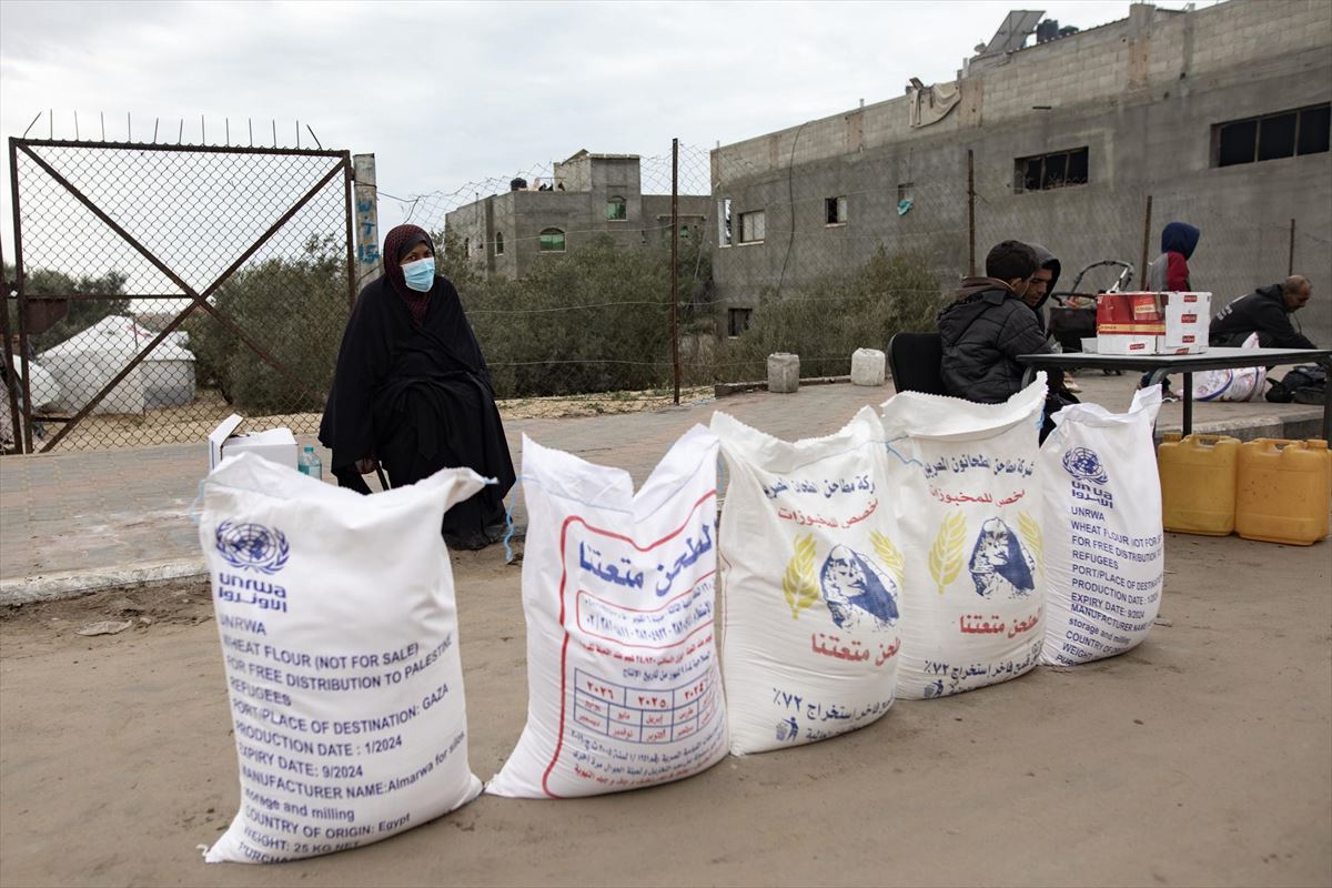 Una mujer en Gaza, delante de sacos de ayuda humanitaria de la UNRWA. Foto: EFE