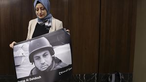 Una mujer sostiene un cartel en recuerdo a un periodista palestino asesinado en Gaza. EFE