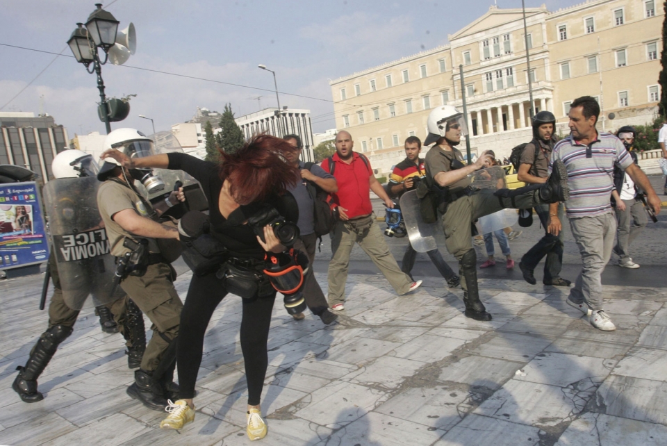 Policías antidisturbios se enfrentan a una fotógrafa y a un periodista en las calles de Atenas. EFE