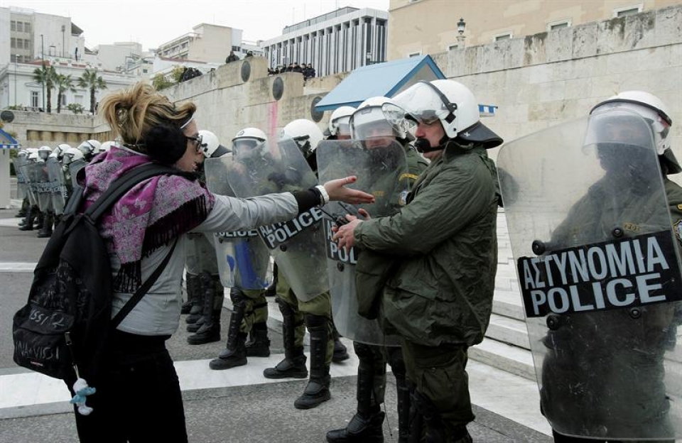Una manifestante habla con policías desplegados a las puertas del Parlamento en Atenas. Foto: Efe.