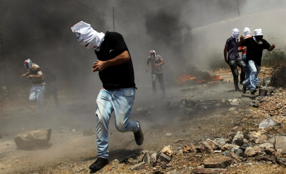 Manifestantes palestinos escapan del gas lacrimógeno lanzado por soldados israelíes.EFE