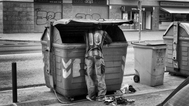 Un hombre busca comida en un contenedor de basura; es España. Foto: Samuel Aranda/The New York Times