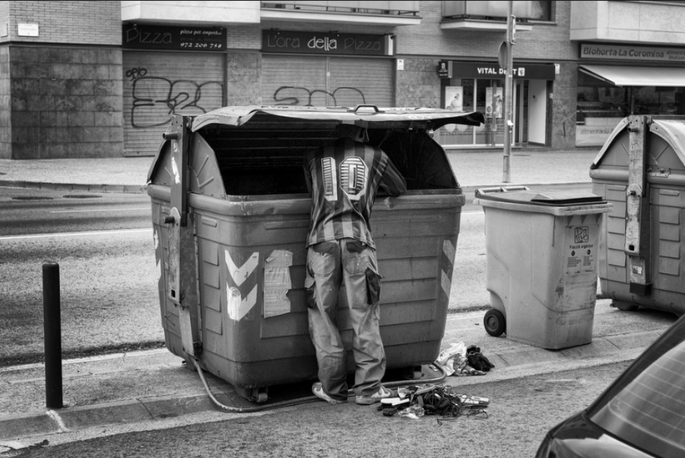 Un hombre busca comida en un contenedor de basura; es España. Foto: Samuel Aranda/The New York Times