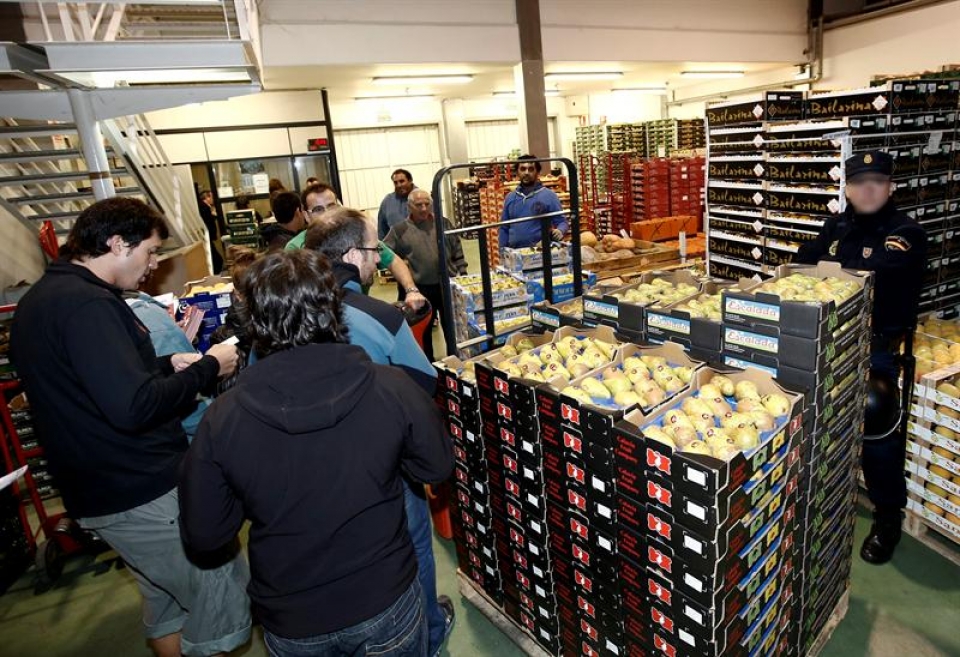 Efectivos de la Policía Nacional, junto a piquetes informativos en Mercairuña. (Foto: EFE)