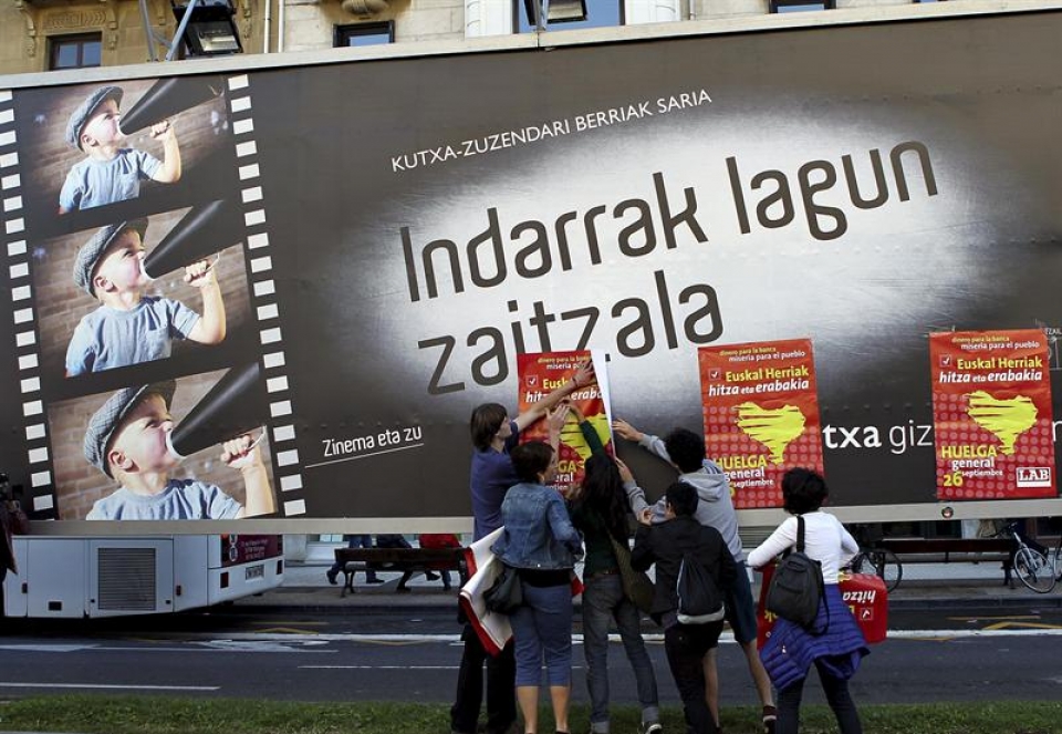 Piquetes informativos colocan carteles sobre otro que anuncia el Festival de Cine de Donostia-San Sebastián. (Foto: EFE)