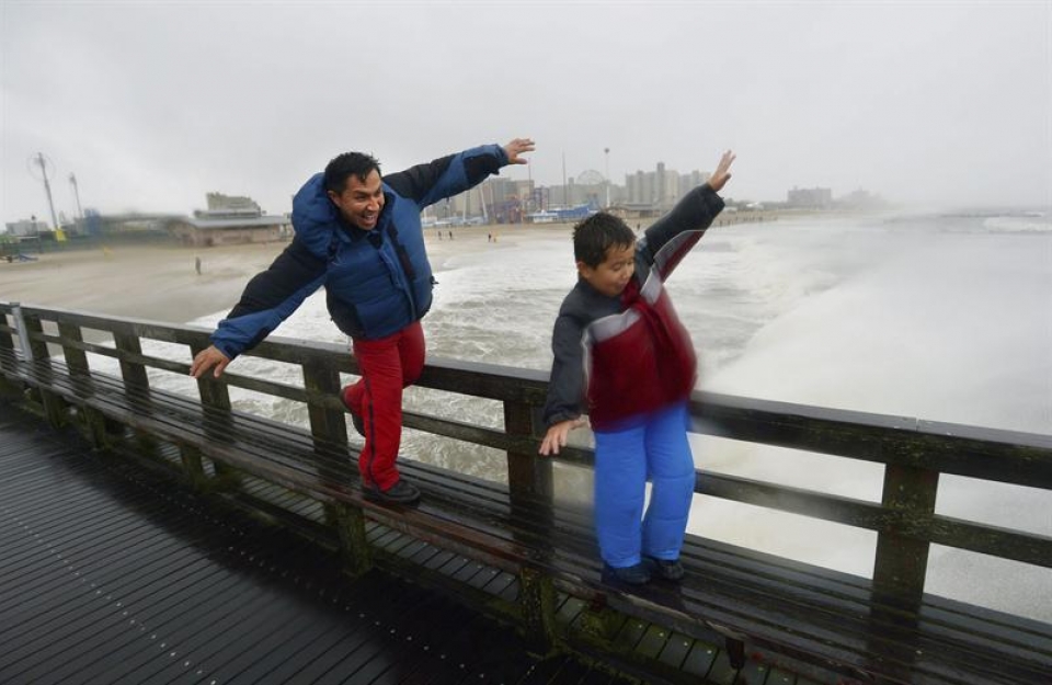 Un hombre y su hijo desafían al viento en Nueva York. (EFE)