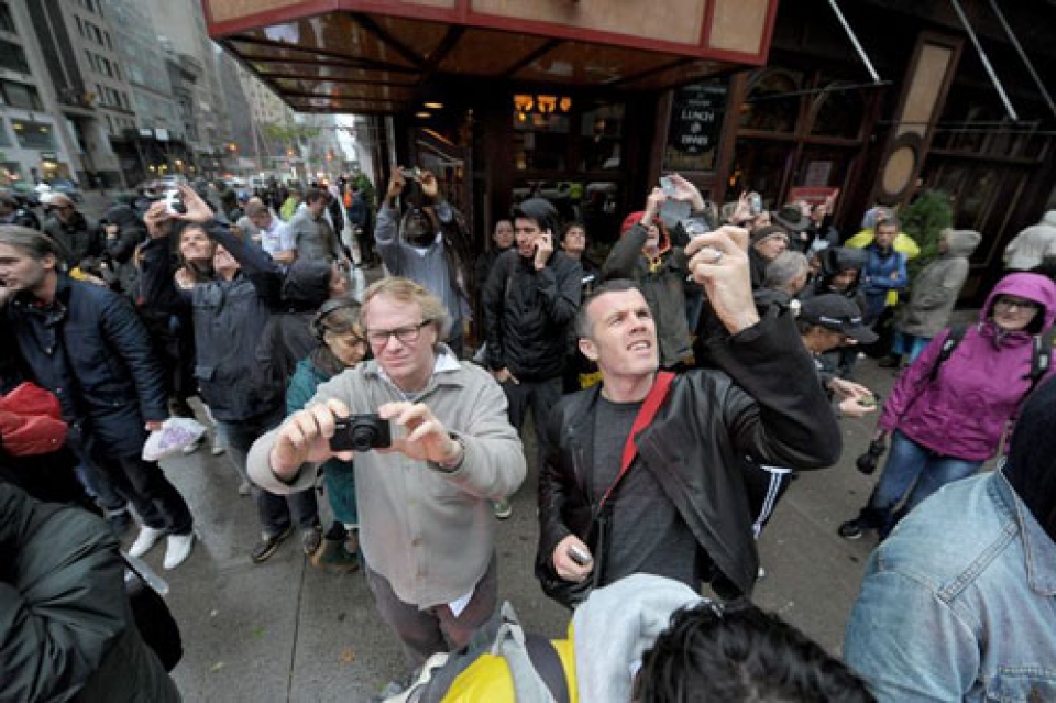 Transeúntes observan la sección de una grúa que cuelga de su base tras partirse. (EFE)