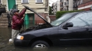 Un hombre intenta reparar su coche con la calle totalmente inundada. (Foto: EFE) title=