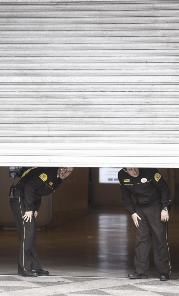 Dos guardas de seguridad tras la persiana de una empresa en Barcelona. Foto: EFE