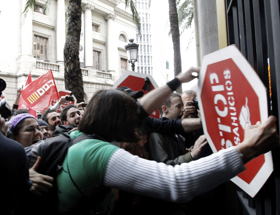 Decenas de huelguistas intentan entrar por la fuerza a la sede del Banco de España en Valencia. Foto: EFE