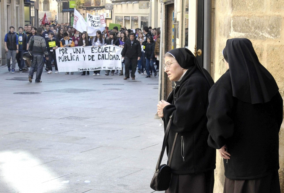 Dos monjas esperan a que pase una maifestación de estudiantes, en Segovia. Foto: EFE