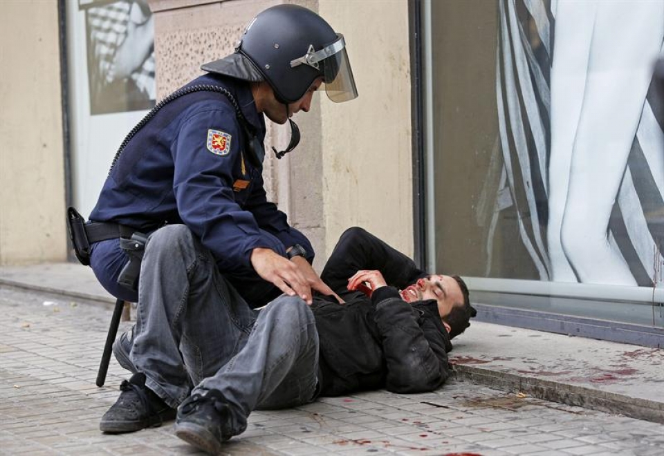 Un policía atiende a un manifestante herido en los altercados de Valencia. Foto: EFE
