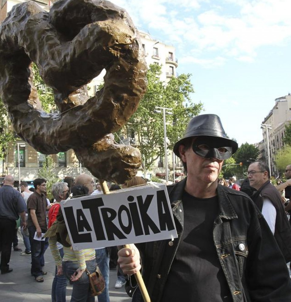 Un hombre sostiene una pancarta durante la manifestación contra la troika en Barcelona. EFE