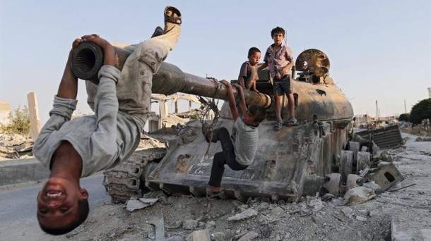 Niños sirios juegan con un tanque destruido en la ciudad de Kobani. Foto: EFE