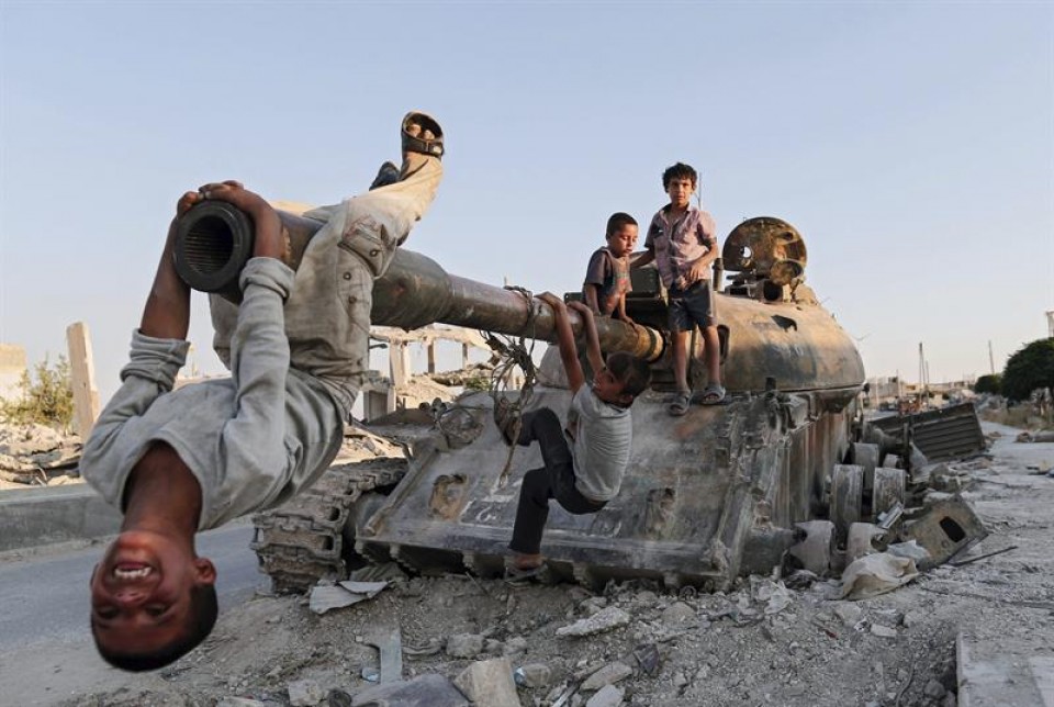 Niños sirios juegan con un tanque destruido en la ciudad de Kobani. Foto: EFE