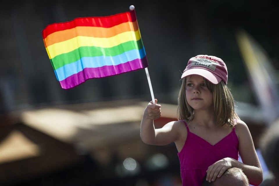 Una niña sujeta una bandera del arcoíris en el día del orgullo gay en Paris